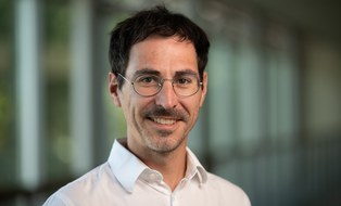 man with dark coloured hair and glasses