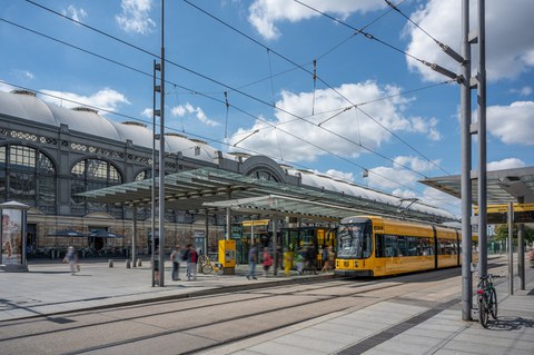 Auf dem Foto der Hauptbahnhof mit der Haltestelle vor dem Hbf, eine Straßenbahn hält, blauer Himmel, die Sonne scheint