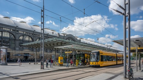 Auf dem Foto der Hauptbahnhof mit der Haltestelle vor dem Hbf, eine Straßenbahn hält, blauer Himmel, die Sonne scheint