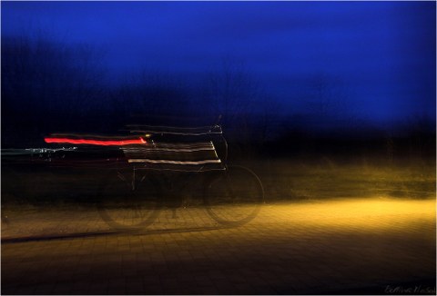 Fahrrad im Dunkeln mit Lichtreflexen auf einem Radweg zur blauen Stunde
