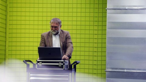 Professor Wolfgang Nagel steht in einem grünen Raum an einem Pult und arbeitet am Laptop