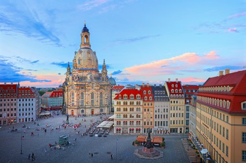 Foto: Altmarkt Dresden mit der barocken Frauenkirche im Hintergrund, umgeben von historischen Gebäuden und einem gepflasterten Platz mit Menschen.