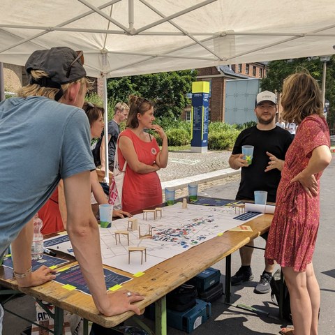 Photo of four people of different status groups talking at a table with a map of the campus