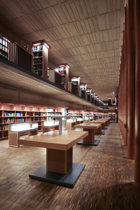 Ein langer, hoher Raum mit großen Stehtischen und Bücherregalen.