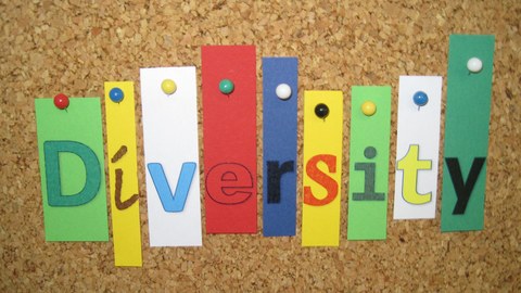 Buchstaben sind an einer Pinnwand befestigt und ergeben das Wort Diversity
