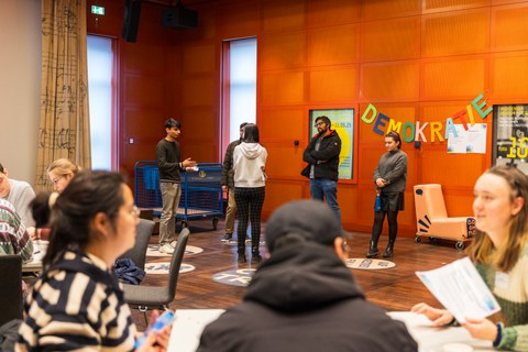 Teilnehmende im Austausch an verschiedenen Stationen des Demokratie-Fitnessstudios