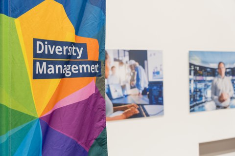 Die Beachflag des Diversity managements vor zwei Bildern des Veranstaltungsraums.