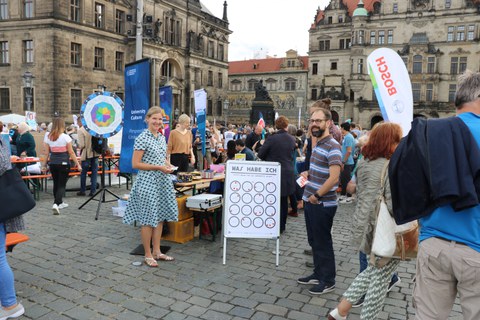 Das Foto zeigt viele Menschen, die einen Stand der TU Dresden beim Gastmahl "Dresden is(s)t bunt" besuchen.