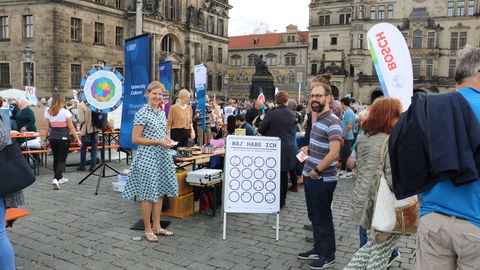 Das Foto zeigt viele Menschen, die einen Stand der TU Dresden beim Gastmahl "Dresden is(s)t bunt" besuchen.