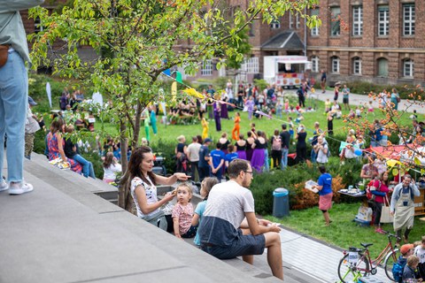 Eine Frau, ein Mann und ihre beiden Kinder sitzen auf den Treppenstufen und überblicken das Familienfest.