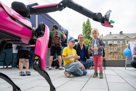 Eine Frau und ihre beiden Kinder beobachten den Roboterhund.