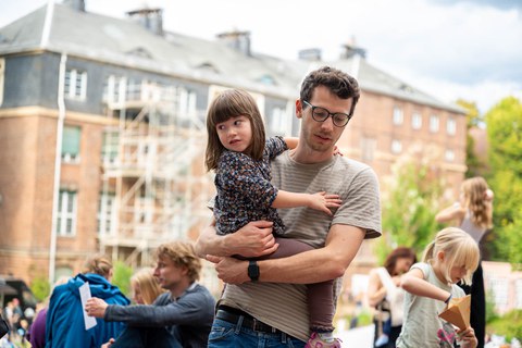 Ein Mann trägt ein kleines Mädchen auf seinem Arm.