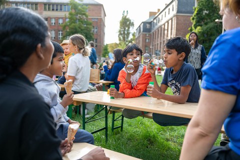 Zwei Jungs sitzen auf einer Bank und machen Seifenblasen.