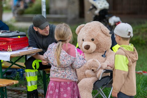 großer Teddy mit Notfallsanitäter und zwei Kindern