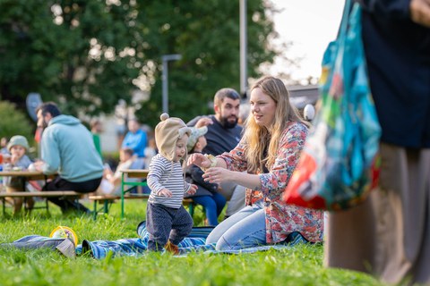 Frau mit Kleinkind auf der Wiese sitzend