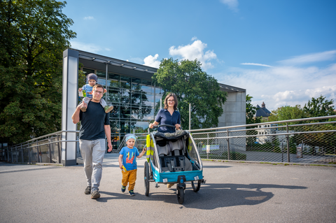 Foto zeigt Eltern mit zwei Kleinkindern und einem Kinderwagen auf dem Campus der TU Dresden.