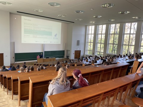 Impression von der Eröffnung des Girls' & Boys' Day 2026 in einem Hörsaal. Schüler:innen verfolgen einen Vortrag mit Powerpoint-Präsentation.