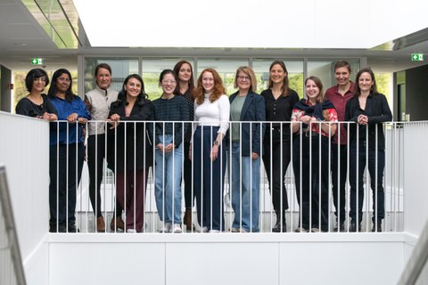 Ein Gruppenbild von 12 Frauen, die hinter einem weißen Geländer stehen.