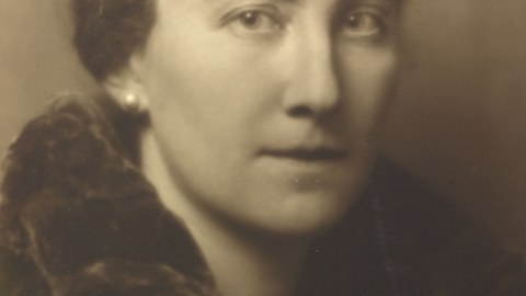 old photograph in brown tones showing a young woman with her hair tied up