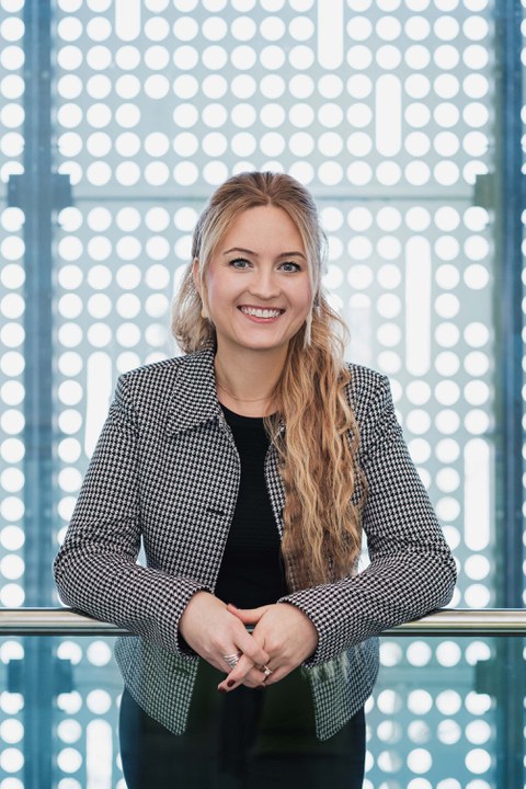 Frau mit langen blonden Haaren schaut in die Kamera.