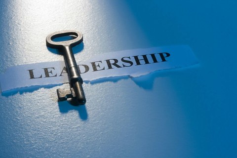 Auf dem Foto ist ein Schlüssel zu sehen der quer über einen kleinen Ausdruck Leadership liegt.
