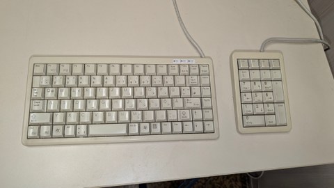 Photo shows a two-part keyboard on the table, with a compact main keyboard on the left and a freely positionable numeric keypad on the right.