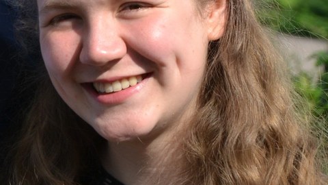 Das Foto zeigt das Portrait einer jungen Frau mit blonden Locken.