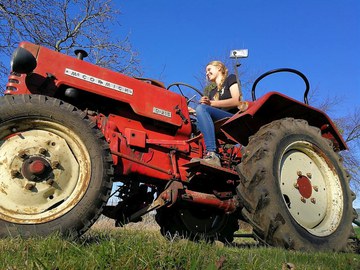 Das Foto zeigt eine junge Frau auf einem roten Traktor.