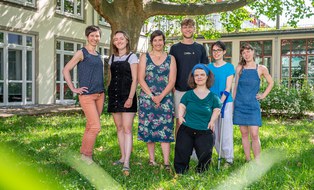 Menschen vor einem Baum posieren gemeinsam als Gruppe für die Kamera