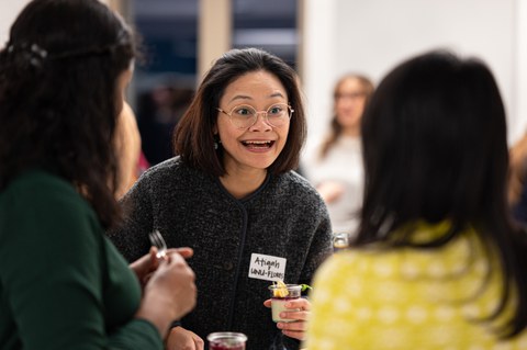 Drei Frauen unterhalten sich, während sie ein Glas Dessert in den Händen halten. Die Mimik einer der Frauen ist positiv überrascht, während sie einer anderen Frau zuhört.