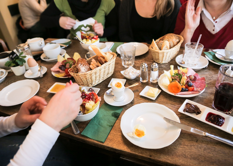 Das Bild zeigt einen bunt gedeckten Frühstückstisch. Mehrere Frauen sitzen an diesem Tisch, essen zusammen und tauschen sich aus.