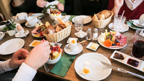 Das Bild zeigt einen bunt gedeckten Frühstückstisch. Mehrere Frauen sitzen an diesem Tisch, essen zusammen und tauschen sich aus.