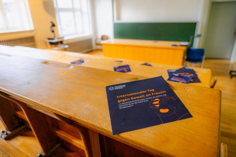 On the bench in the lecture hall is the programme booklet for the International Day against Violence against Women.