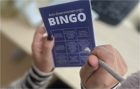 Ein Person hält das Anti-Diskriminierungs-Bingo in der Hand
