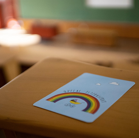 A postcard for the "Queer Parenthood" event series is on a table in the lecture hall. 