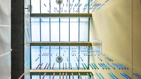 Foto nach oben auf die Kunstinstallation von Roland Fuhrmann mit bunten hängenden Röhren im Chemiebau.