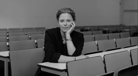 Schwarz-Weiß-Porträt. Lisa Niendorf sitzt im Hörsaal. Sie stützt ihre Hand auf.