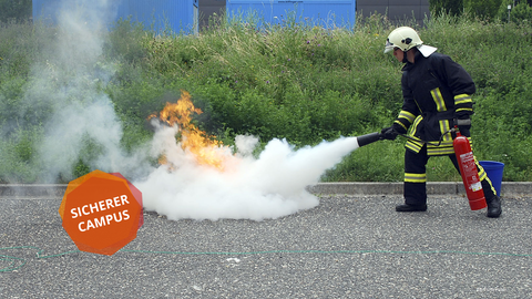 Ein Feuerwehrmann nutzt einen Feuerlöscher, um ein Feuer für Demonstrationszwecke zu löschen.