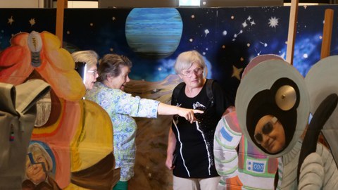 3 Personen stehen in einer Kunstinstallation, die nach Weltall und Raumstation aussieht.