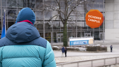 Das Foto zeigt das Hörsaalzentrum der TU Dresden. Eine Person mit dem Rücken zur Kamera. Ein Button mit der Aufschrift "Sicherer Campus".