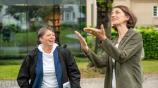 Prorektorin Böhm weist mit beiden Händen in ein Richtung und Staatssekreträin Dr. Märtens blickt sie an
