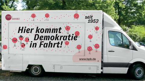 Das Bild zeigt einen Kleinbus mit der Aufschrift "Hier kommt Demokratie in Fahrt".