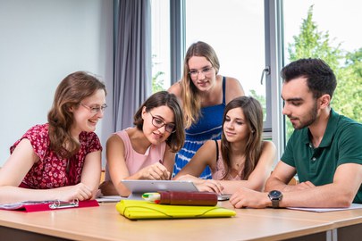 Foto von fünf Studierenden, die in einer Workshoprunde zusammen am Laptop arbeiten