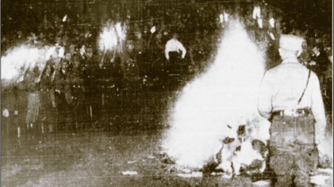 Es handelt sich um eine schwarz-weiß Fotografie von sehr schlechter Qualität. Sie zeigt eine Szene bei der Bücherverbrennung am Bismarckturm am 10. Mai 1933. Zu sehen sind einige lodernde Scheiterhaufen um die uniformierte Menschen stehen.