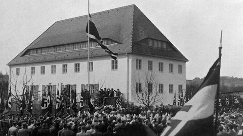 A historical black-and-white photograph showing the flag-raising ceremony for the dedication of the Nazi Student Union building in April 1936.