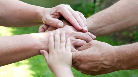 Auf dem Foto sieht man die Hände mehrerer Personen unterschiedlichen Alters, die übereinander liegen und sich gegenseitig halten.