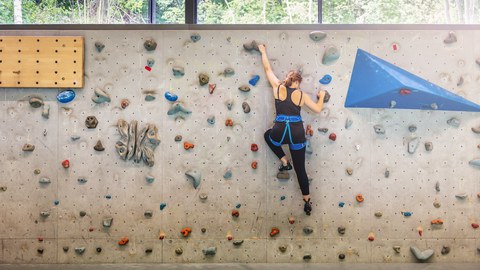 Foto einer Frau an einer Kletterwand in einer Halle