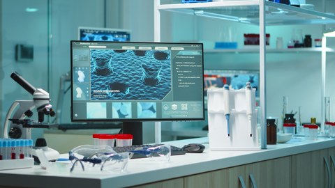 Laborinterieur mit Mikroskop und Monitor im Vordergrund 