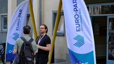 2 Personen im Eingangsbereich zur konferenz - zwischen 2 Beach-Flags mit der Beschriftung Euro-Par 2025 (Logo der Veranstaltung)