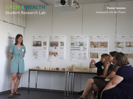 Poster Session, Austausch mit der Praxis, an der Wand hängen Poster, eine Frau steht vorne, 3 Frauen sitzen gegenüber